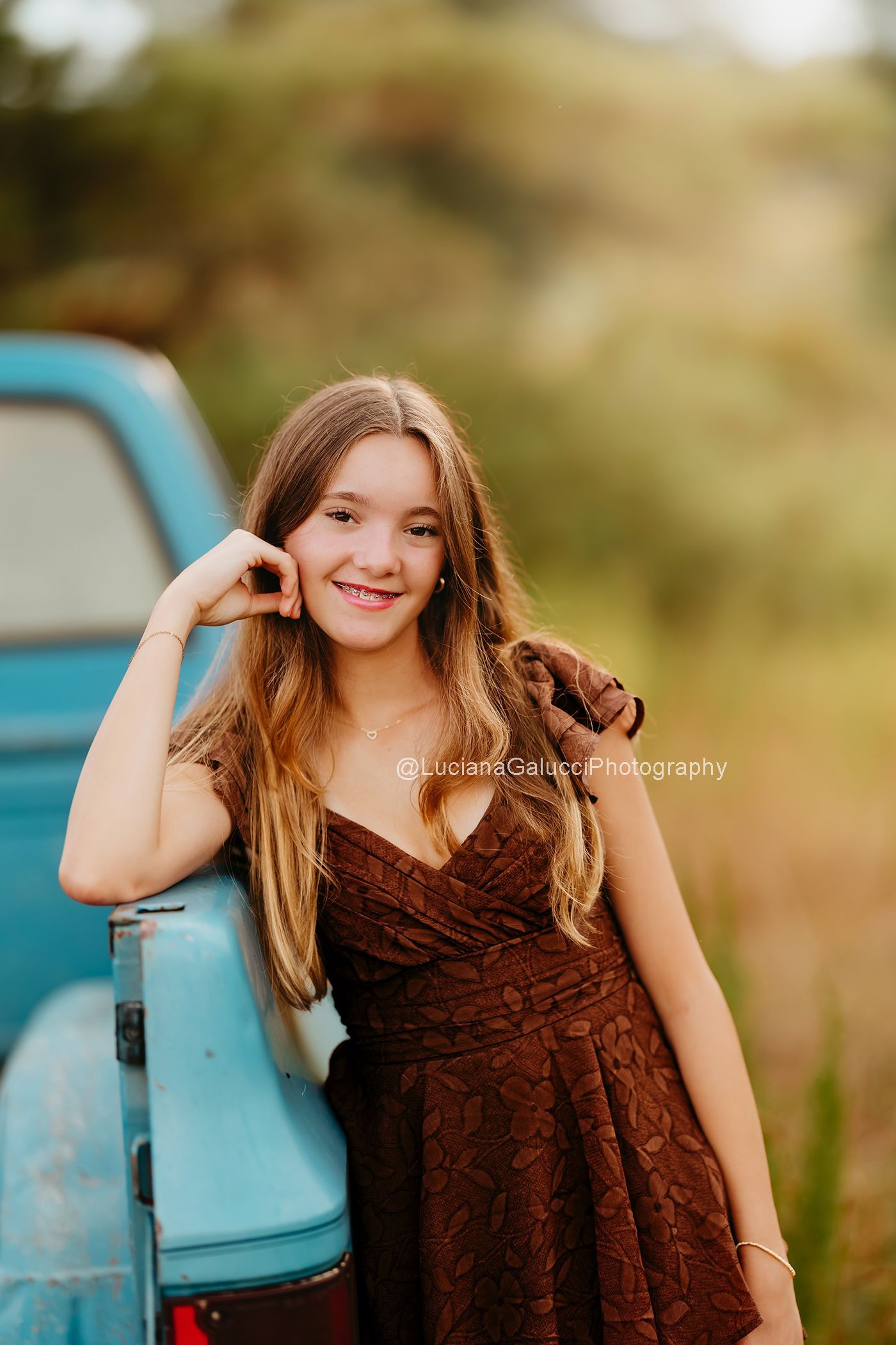 Teenager girl  Smiling beside a vintage blue truck at a private farm during a Raleigh Portrait session.