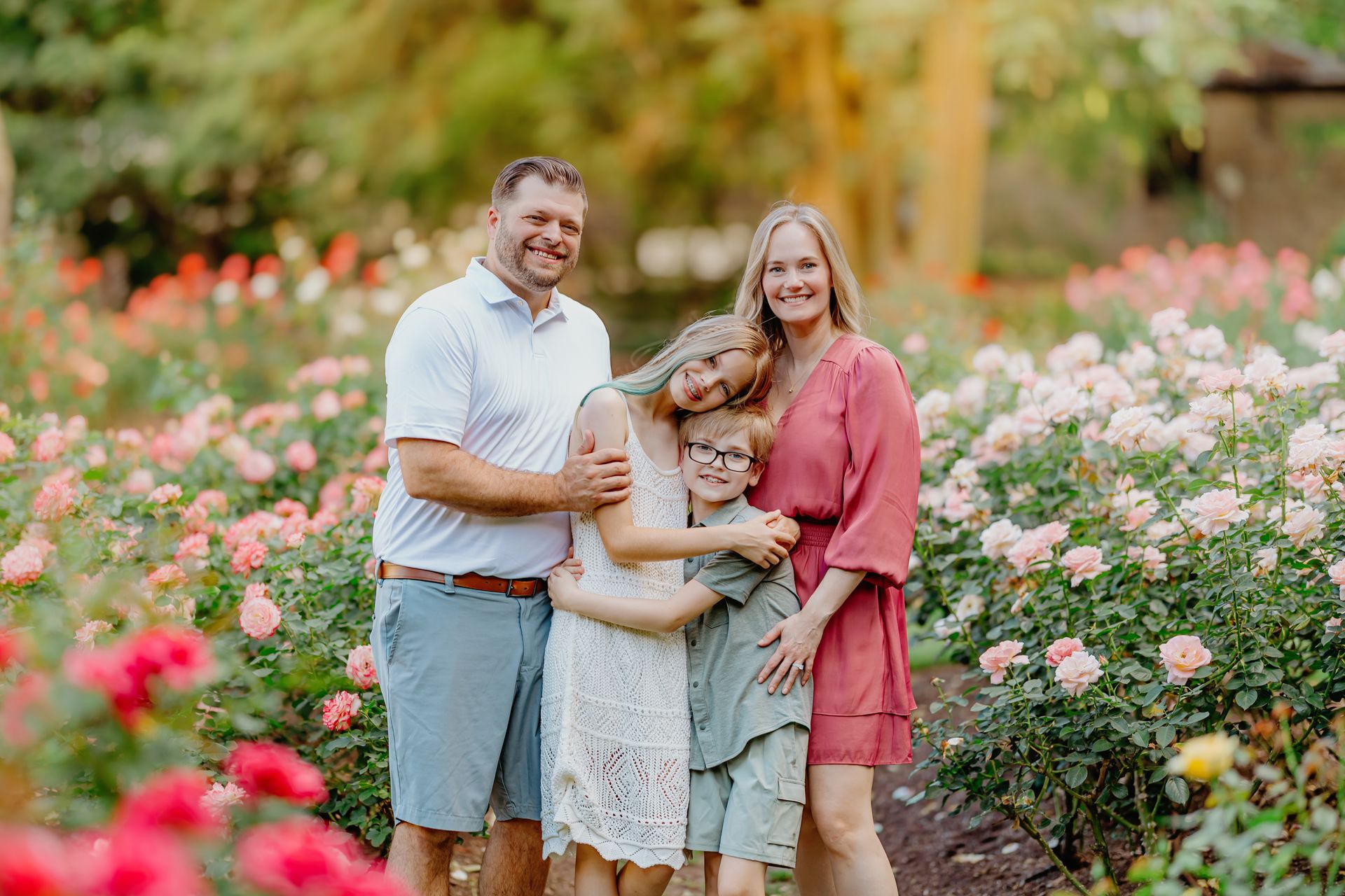 Family smiling and posing in the blooming Raleigh Rose Garden during golden hour