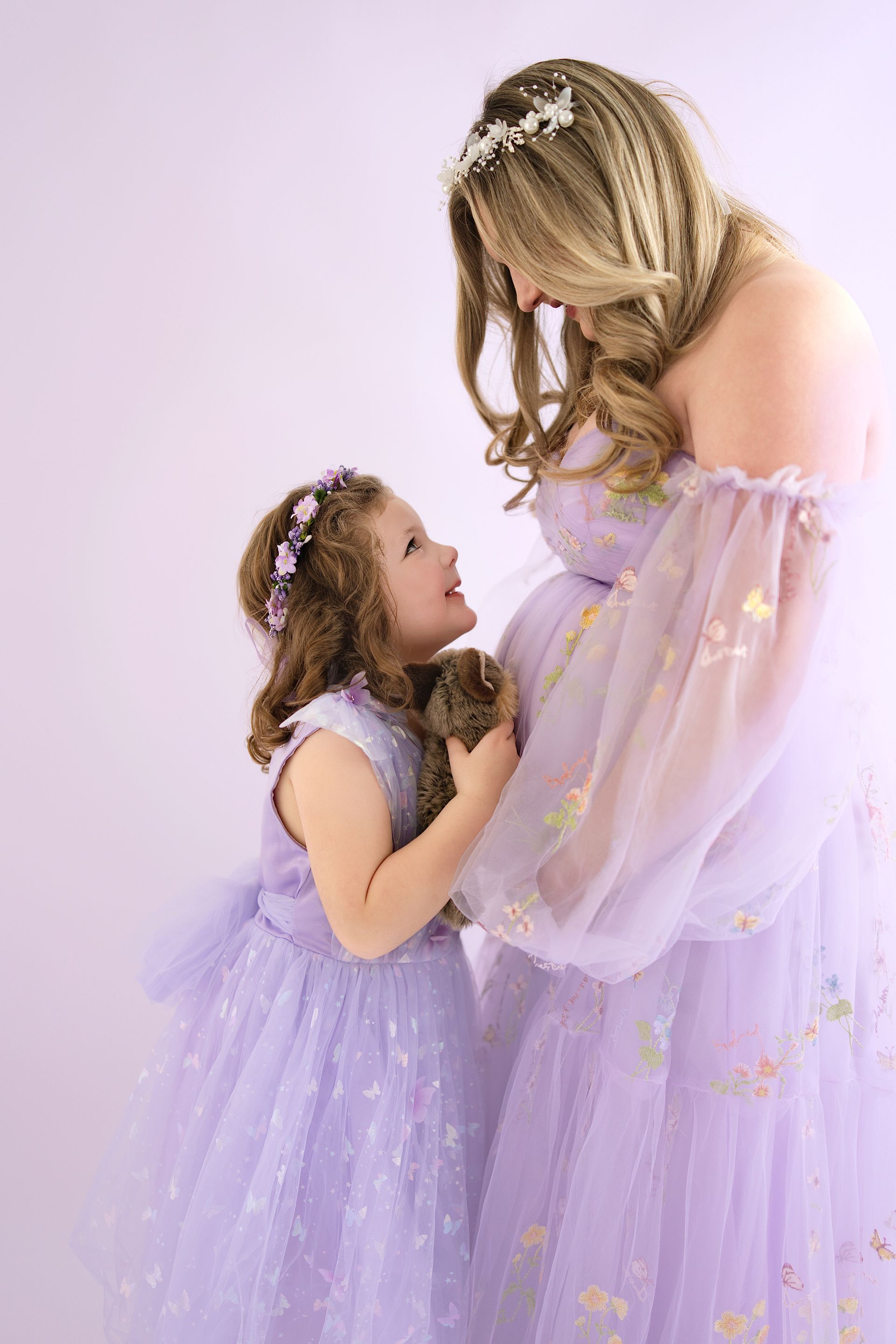 Pregnant mom and 4-year-old daughter sharing a sweet moment before baby sister arrives