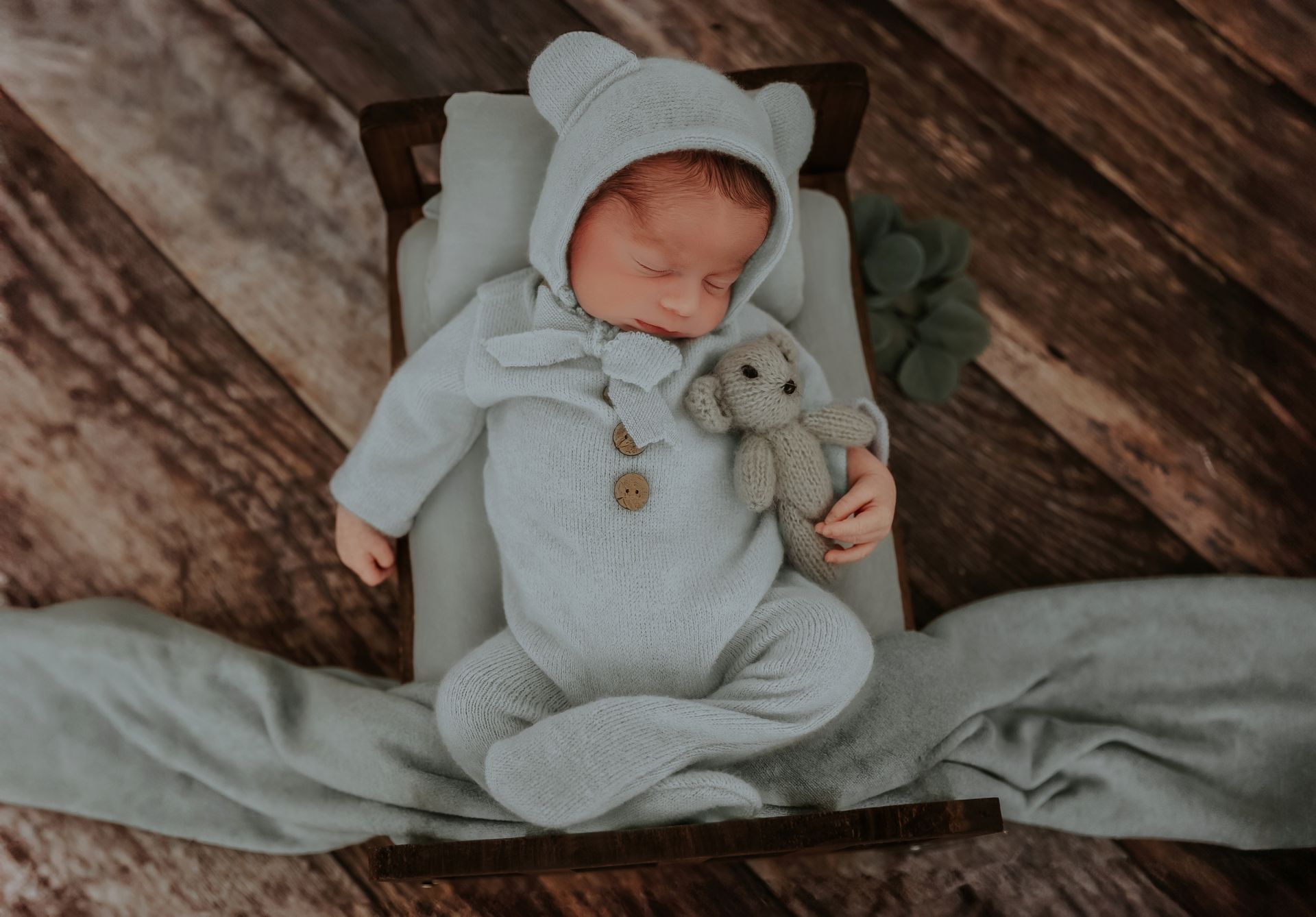 Sleeping newborn baby in blue outfit during Cary studio session