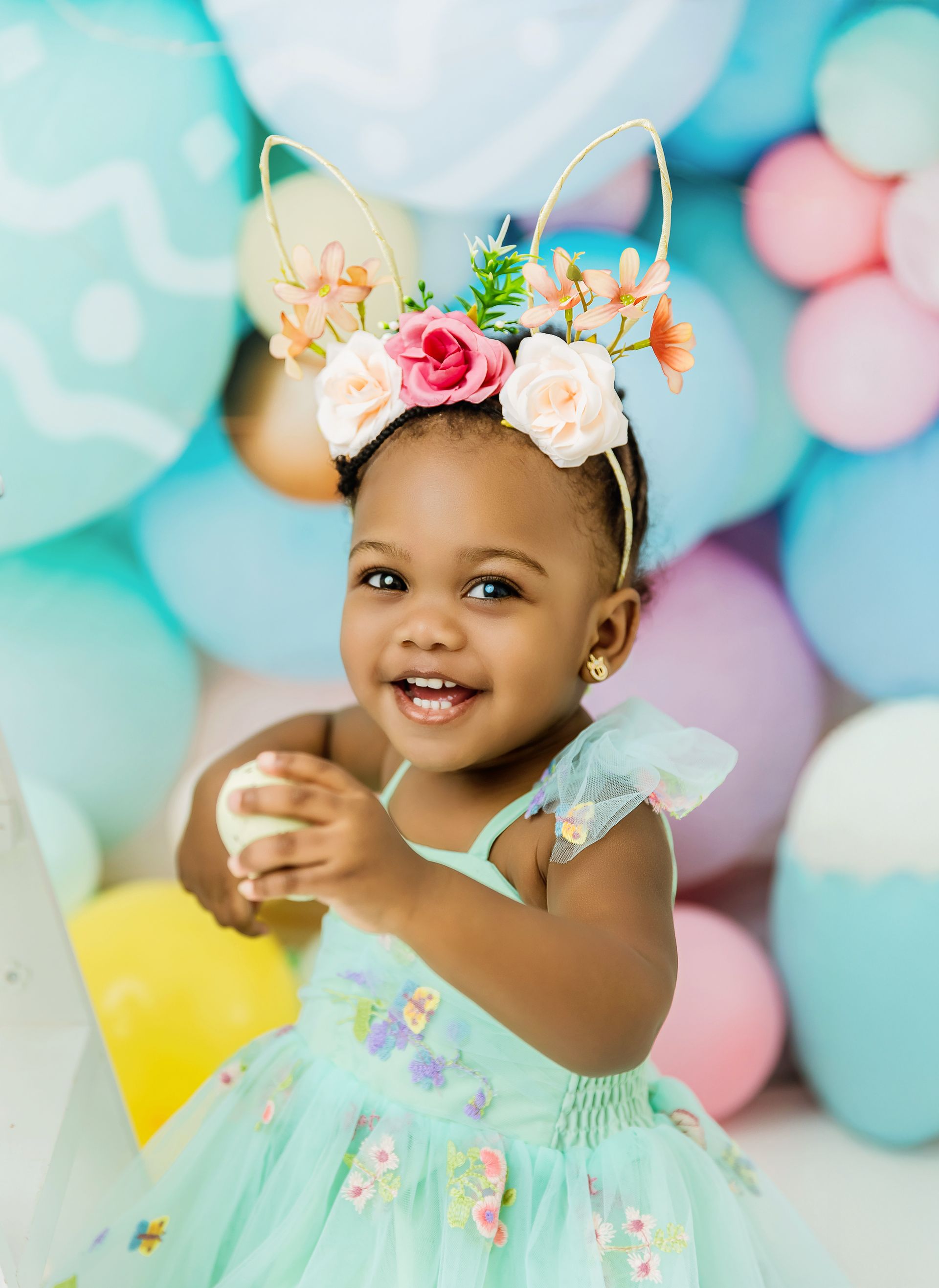 Toddler girl smiling in a pastel Easter studio mini session in Cary, NC with colorful backdrop