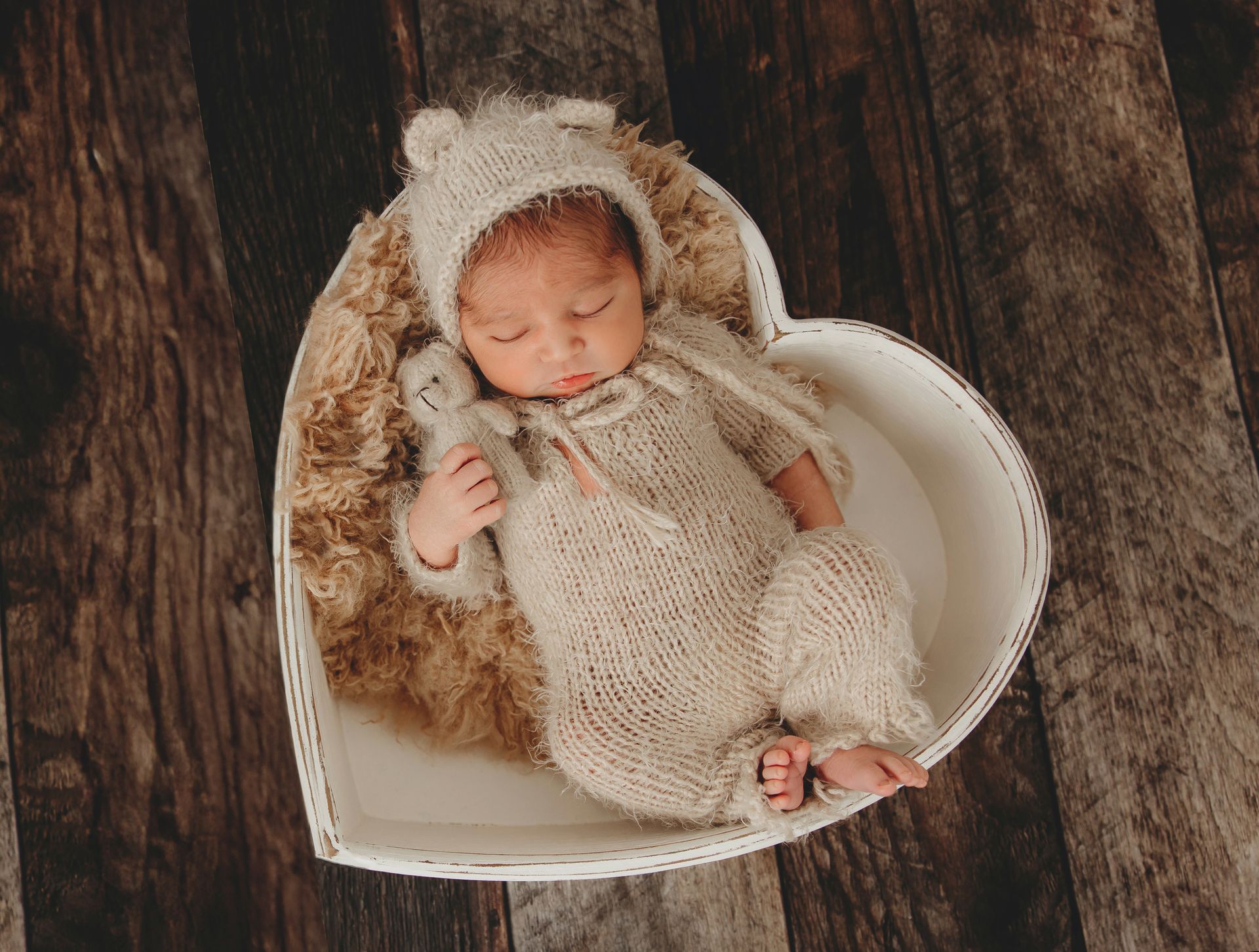 Newborn boy portrait in a heart bow holding a teddy bear in Cary, NC studio