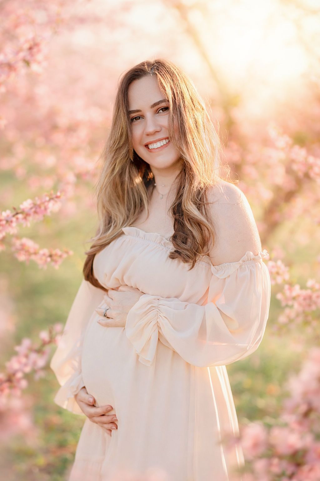 Pregnant mother smiling during peach blossom maternity session in Raleigh NC orchard