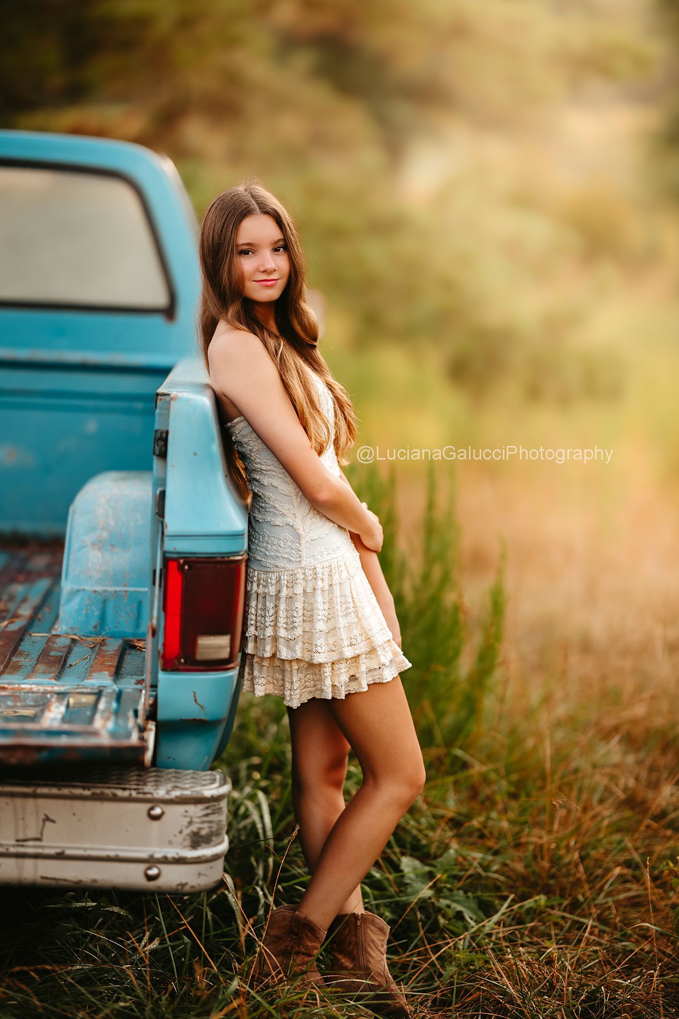 Teen girl  standing beside a vintage blue truck at a private farm during a Raleigh Portrait session.
