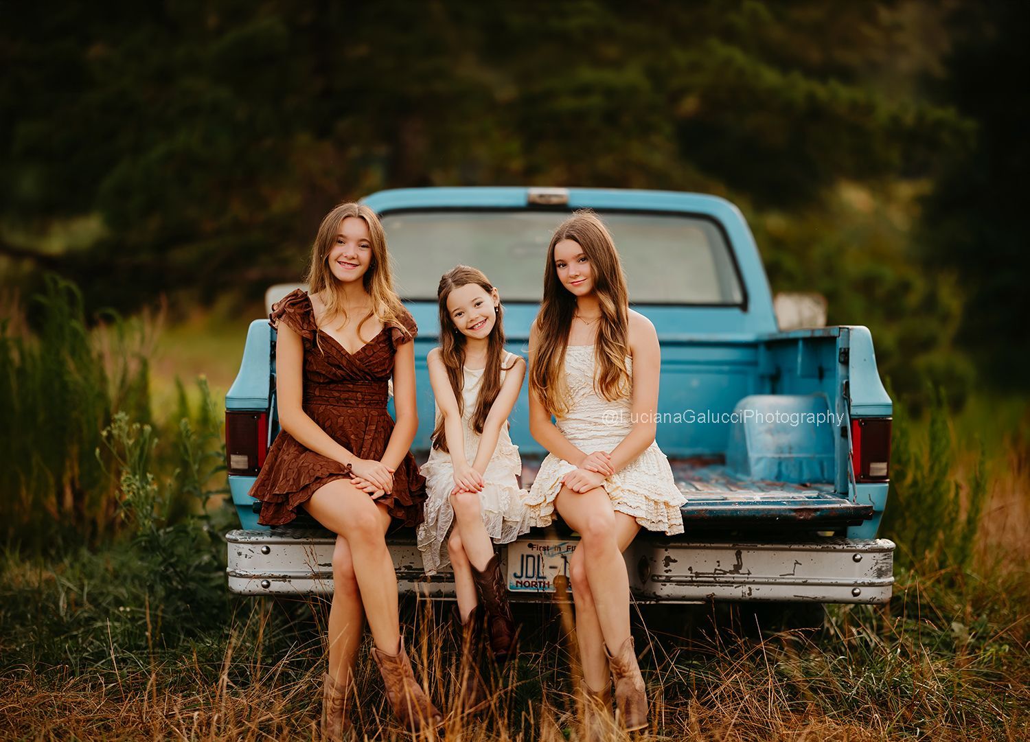 Three sisters posing together in a Blue truck  photo session at a private farm near Raleigh, NC.