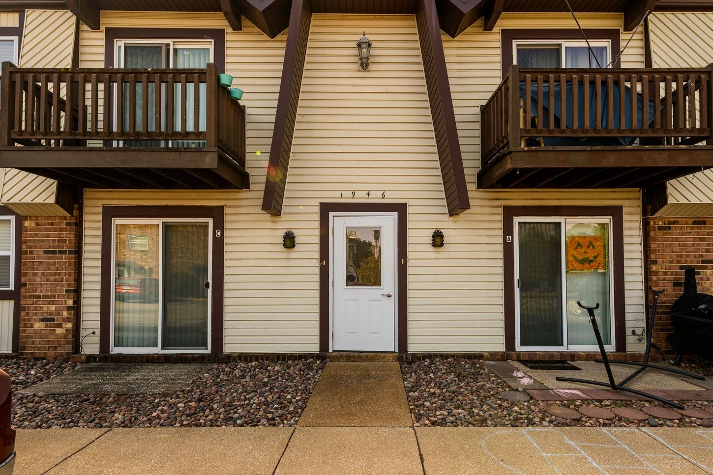 Exterior view of a two-story apartment building with balconies, a white door, and large windows.