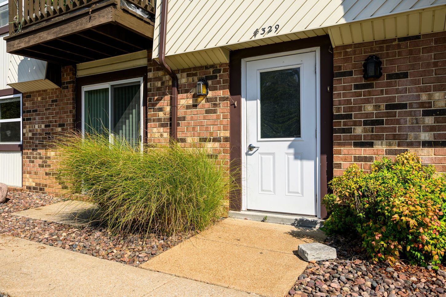 Entrance to a building at 4331, with a white door, windows, brick, and landscaping.