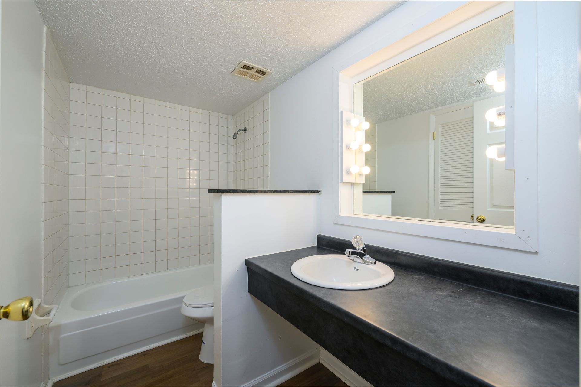 Bathroom with white tile, a bathtub, a sink, and a large mirror.