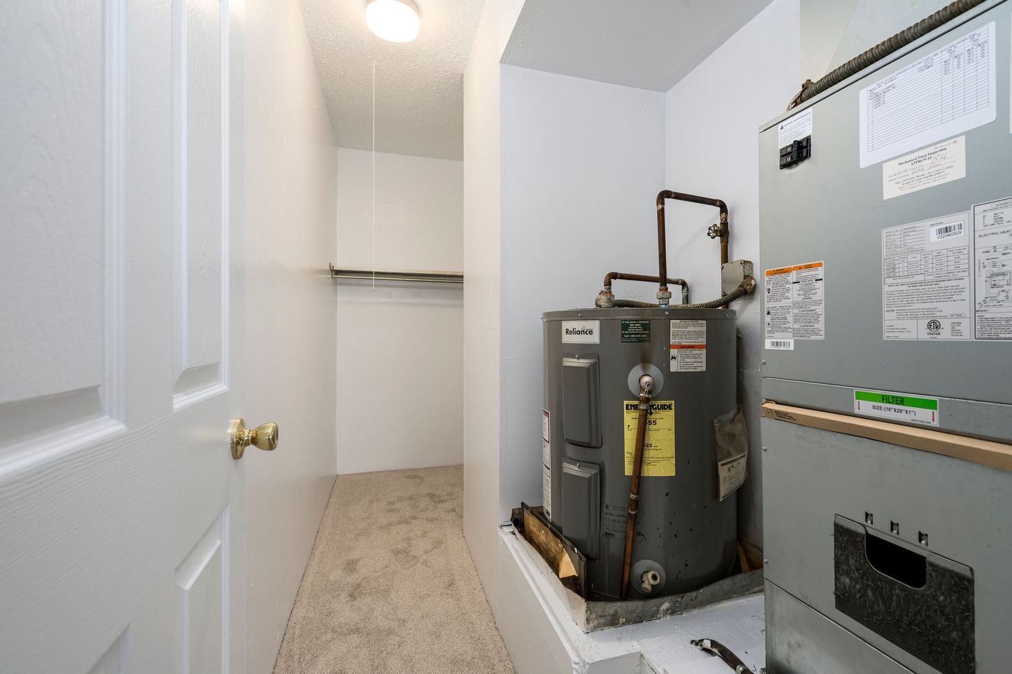 A small utility room with a water heater, HVAC unit, and a closet.