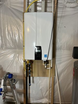 A white water heater is mounted to a wall in a garage.