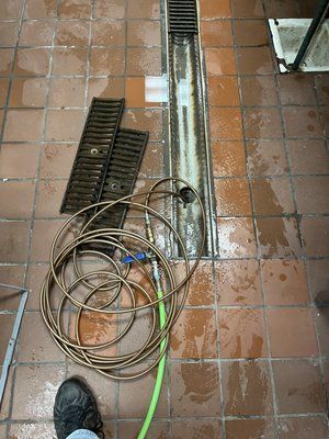 A person is standing next to a hose on a tiled floor.