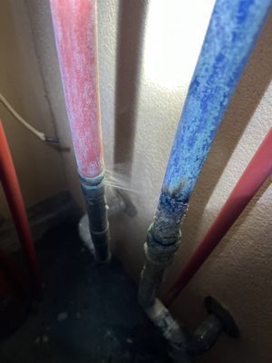 A close up of a red and blue pipe with water coming out of it.