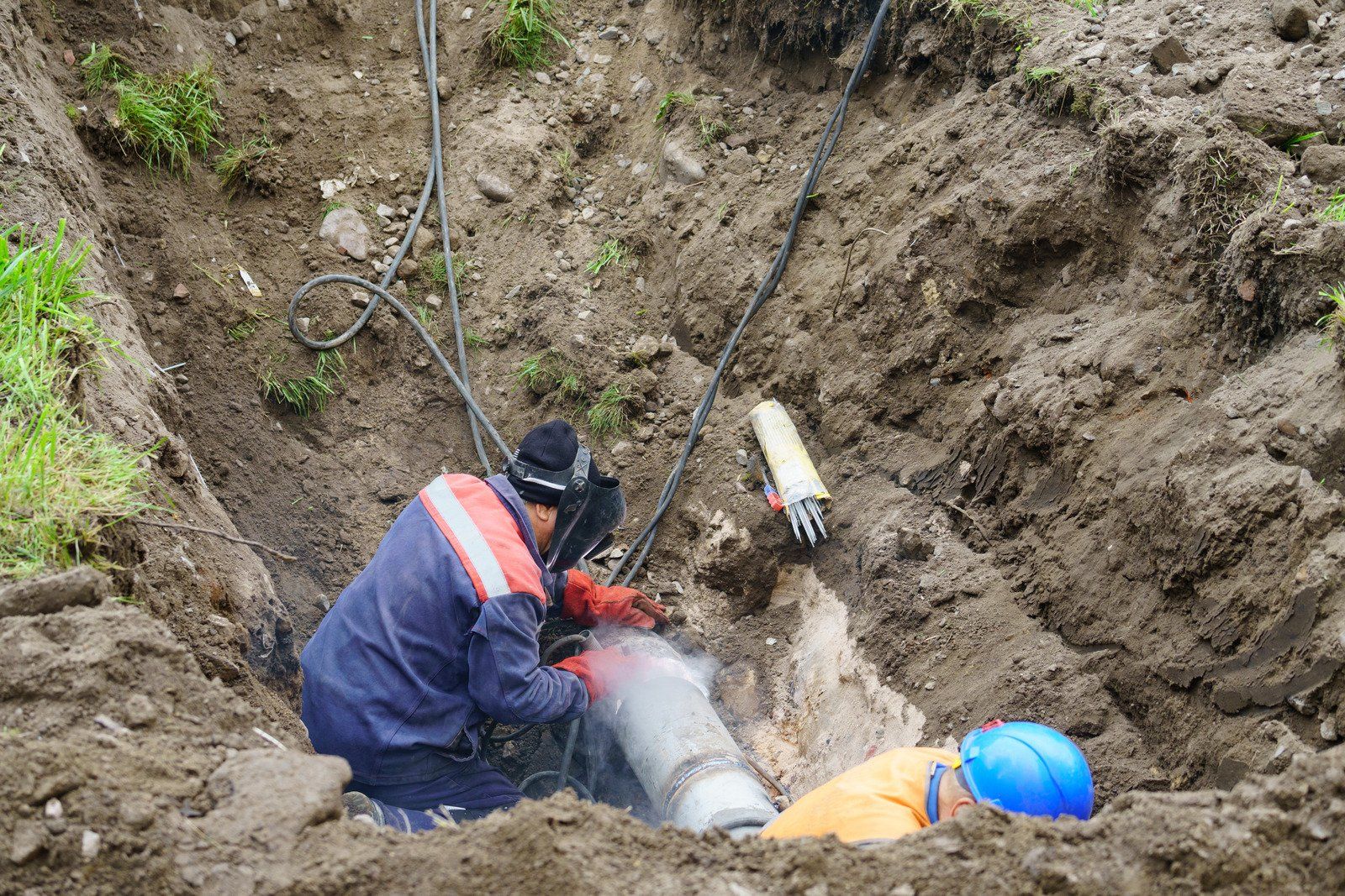 A man is working on a pipe in the dirt.