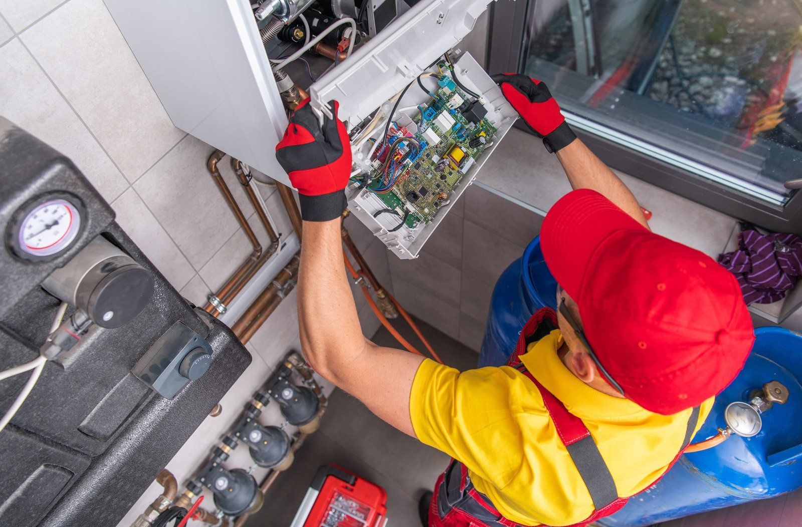 A man is working on a boiler in a room.