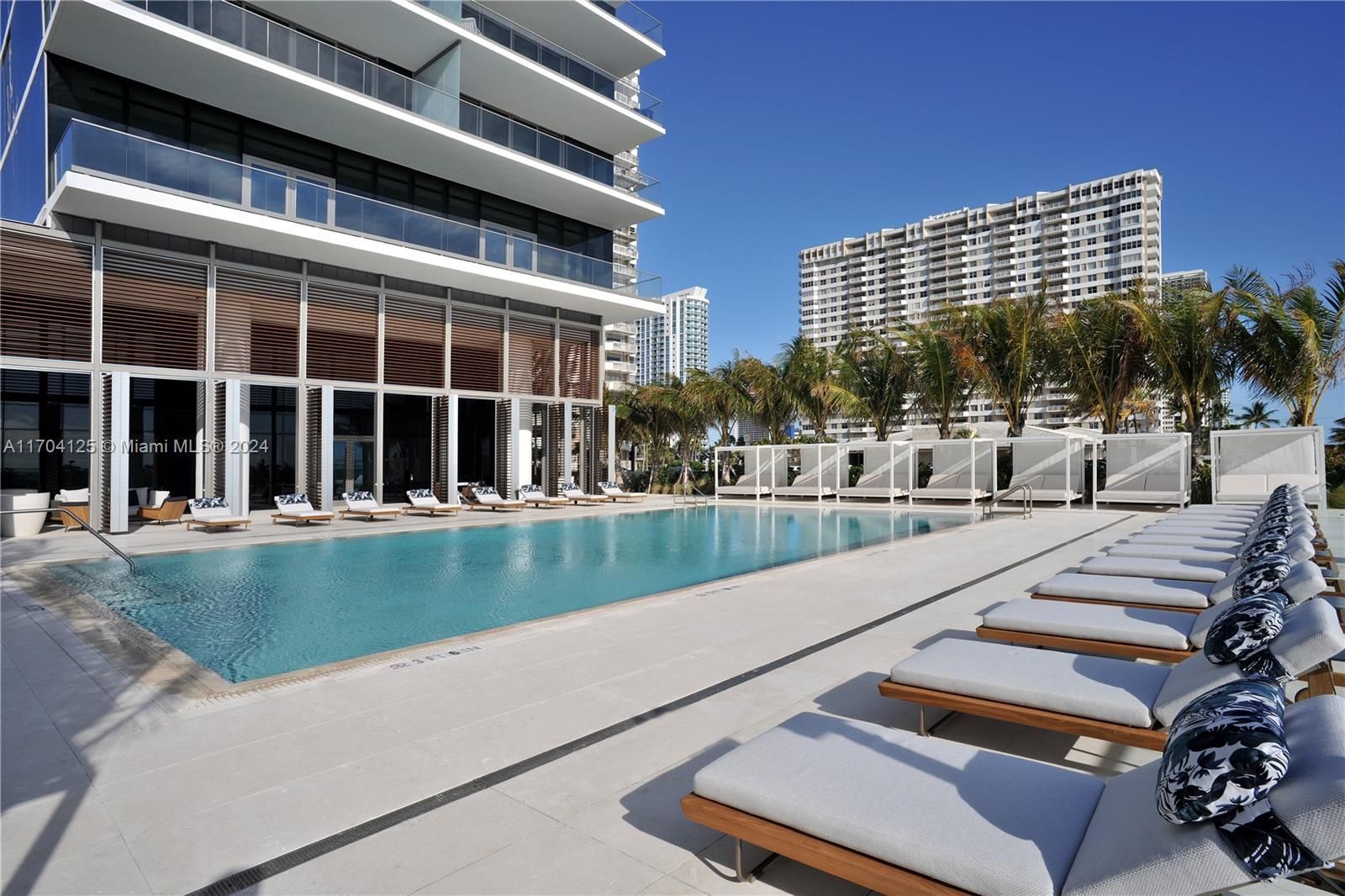 Poolside view of a luxury high-rise building in Miami, with lounge chairs and a swimming pool.