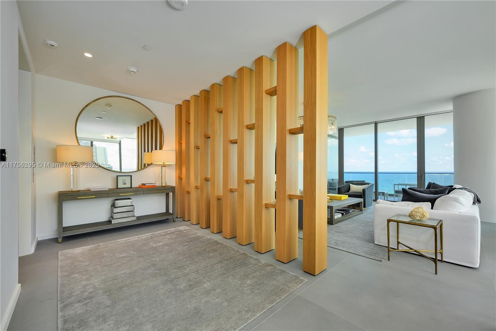 Modern apartment interior with wooden room divider and ocean view.