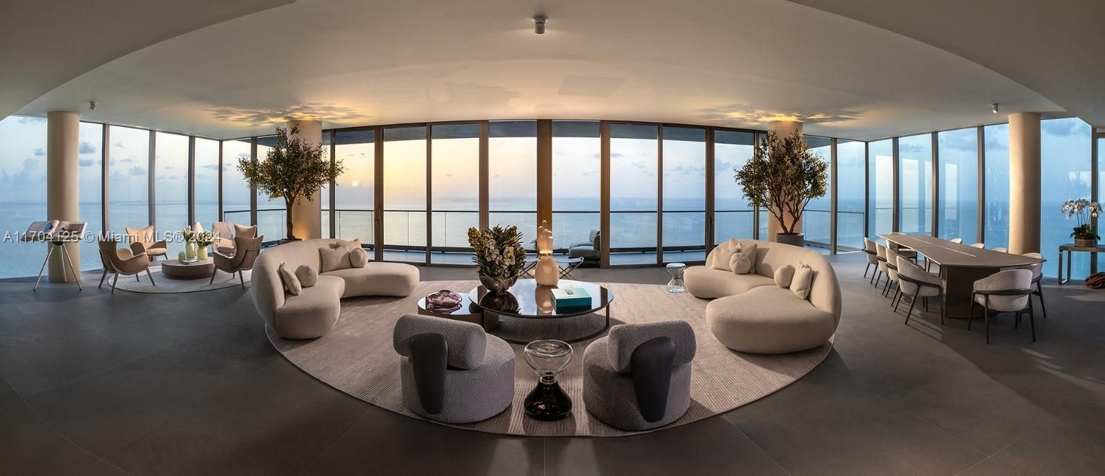 Luxurious modern living room with curved sofas, floor-to-ceiling windows, and ocean view.