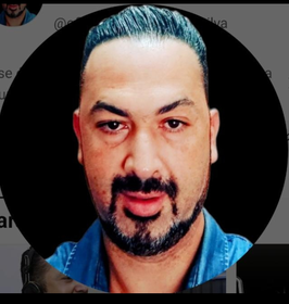 Um homem com barba e cabelo azul está em um círculo