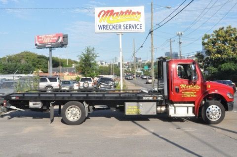 Red tow truck parked on a street in front of 