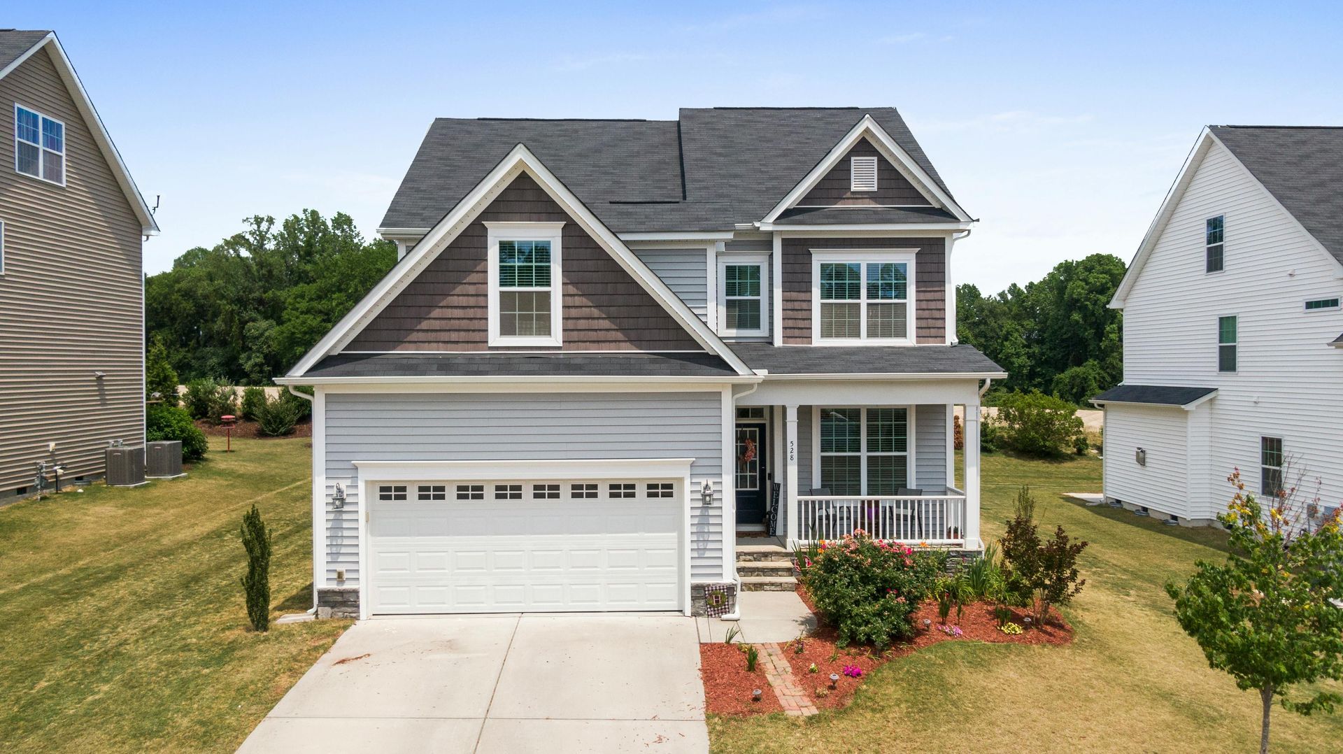 A large house with a white garage door is sitting on top of a lush green field.