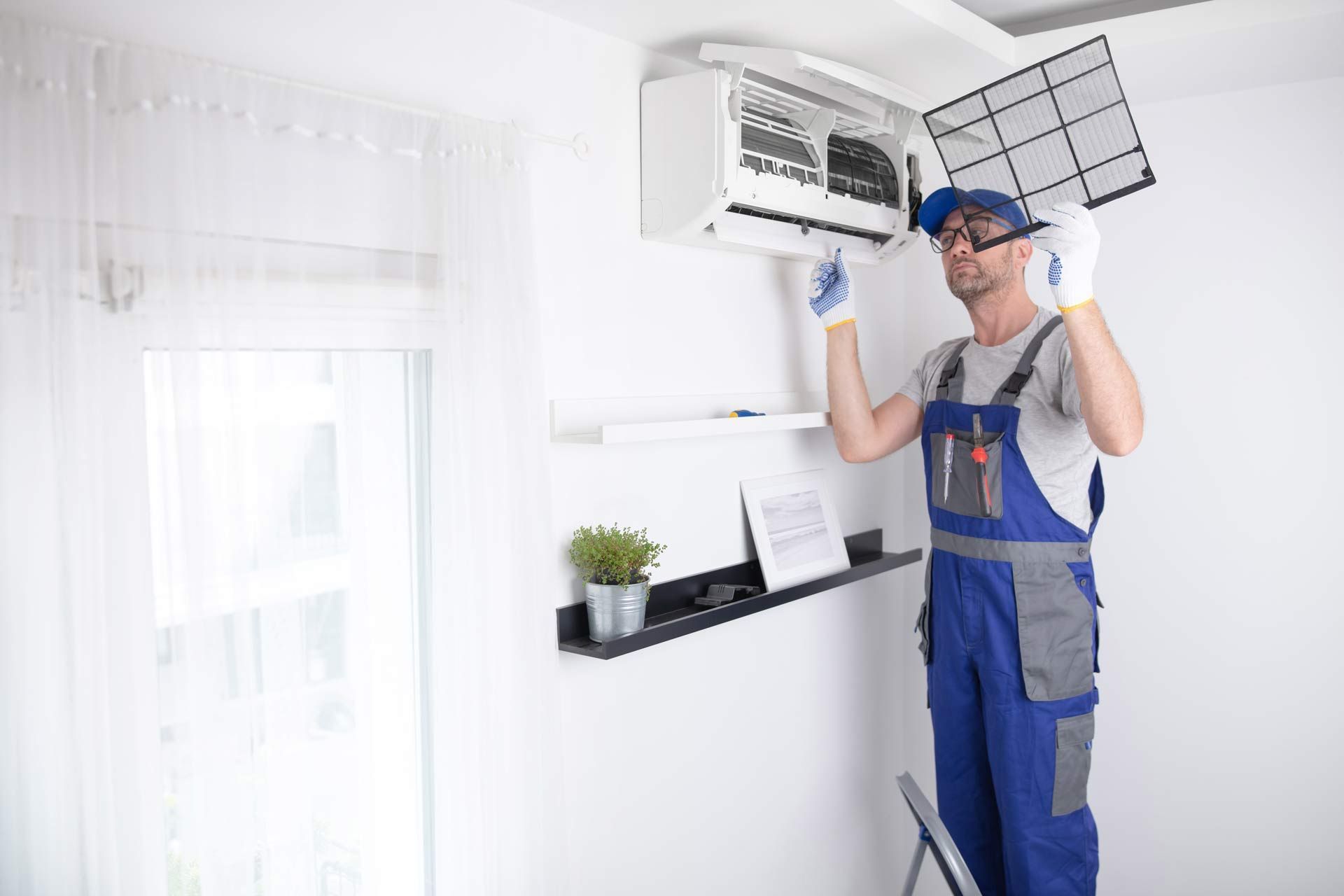 A man is working on an air conditioner in a living room.