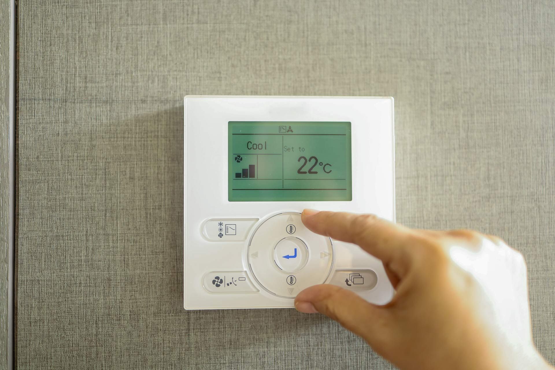 A person is pressing a button on a thermostat.