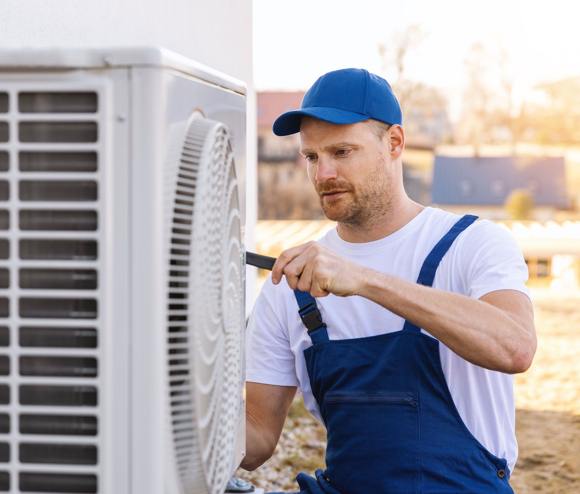 A man is fixing an air conditioner with a screwdriver.
