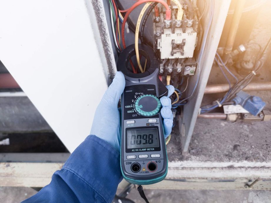 A person is holding a digital multimeter in their hand.