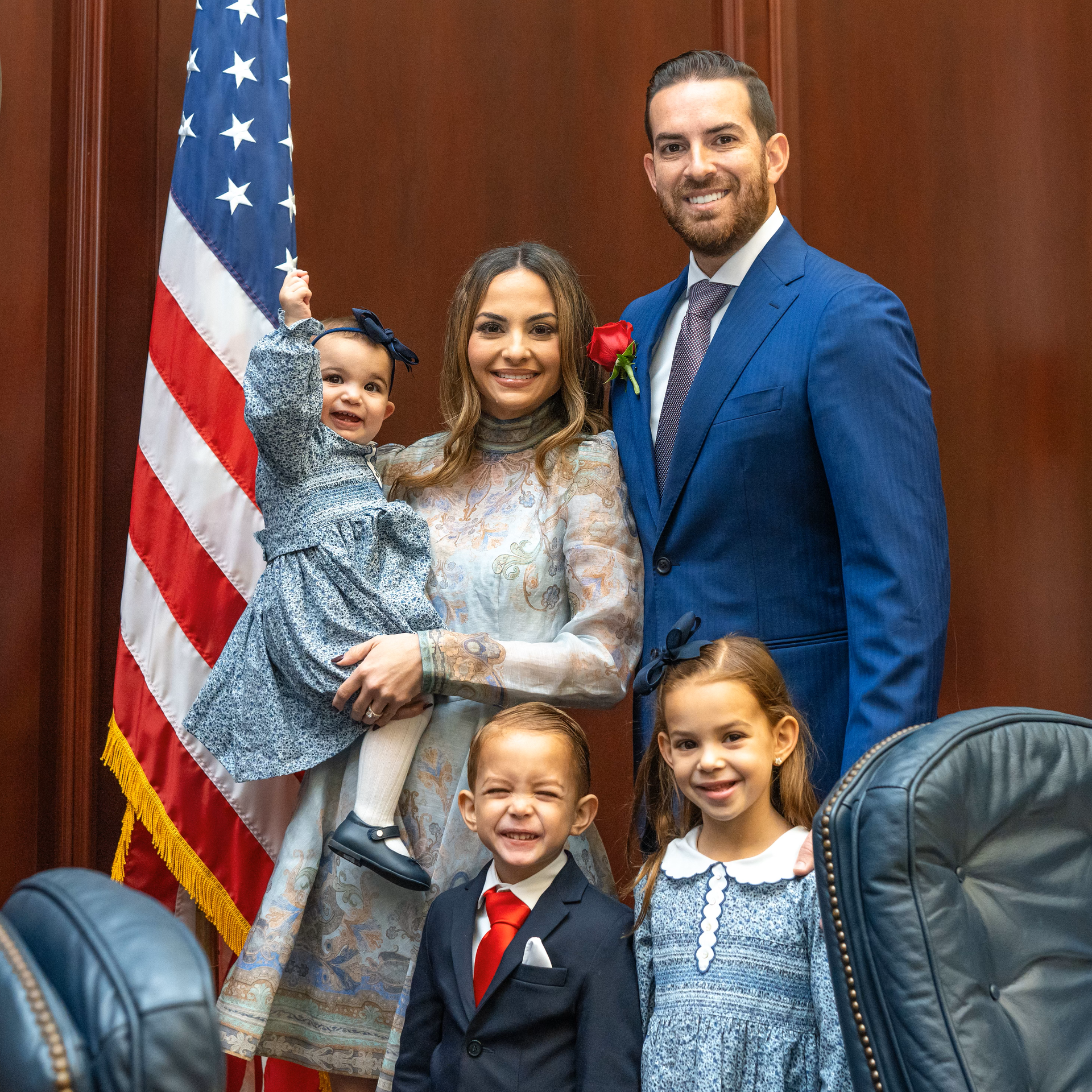 A family is posing for a picture in front of an american flag.