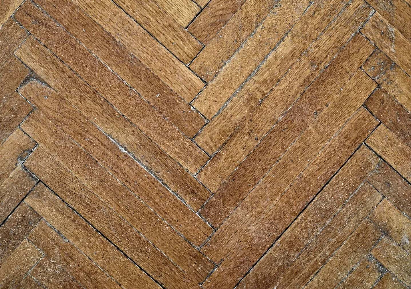 A close up of a wooden floor with a herringbone pattern.