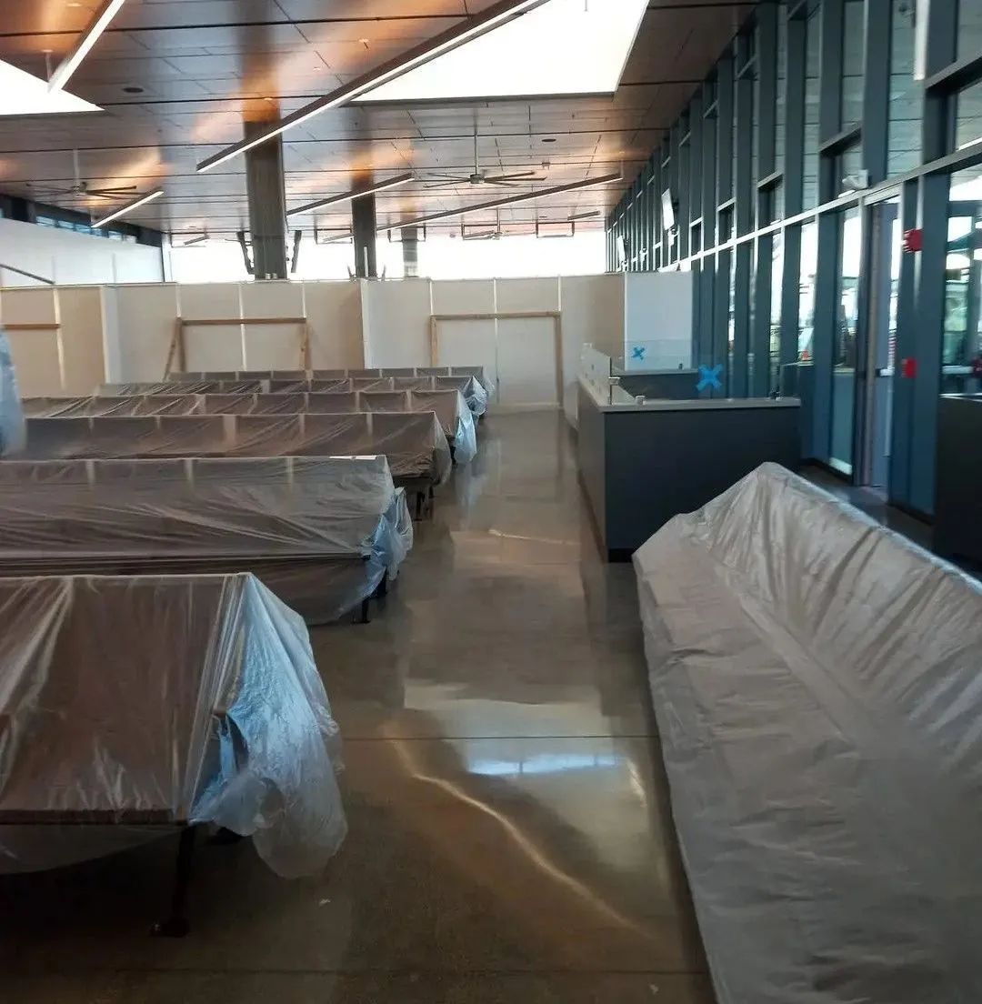 A large room with a lot of tables and chairs covered in plastic