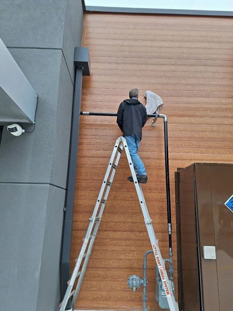A man is standing on a ladder on the side of a building.