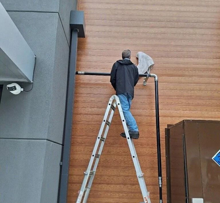 A man is standing on a ladder on the side of a building.