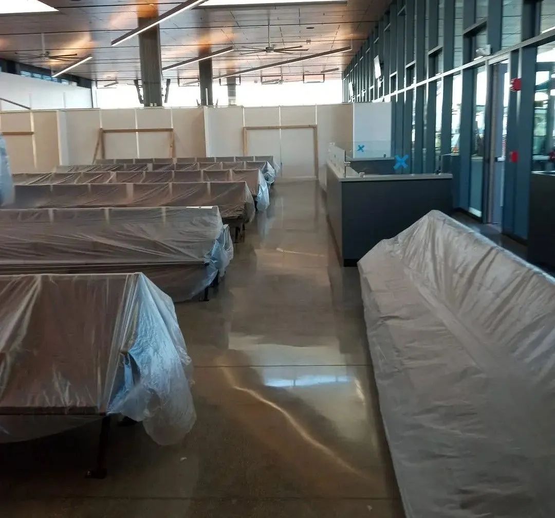 A large room with a lot of tables and chairs covered in plastic