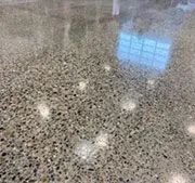 A close up of a shiny concrete floor with a window reflected in it.