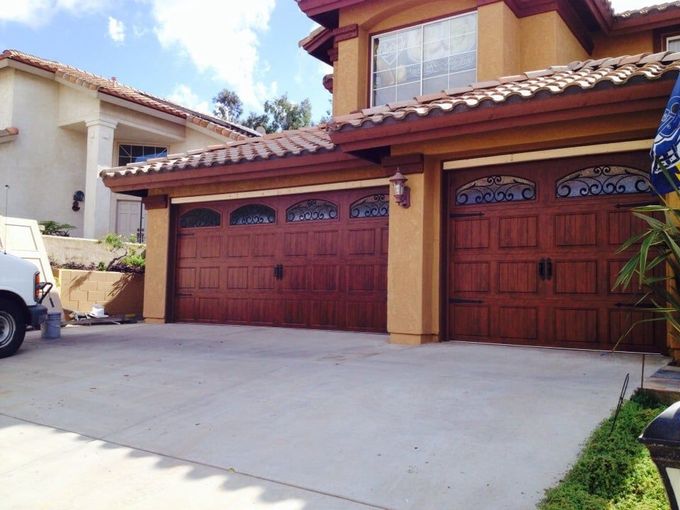 Dark gray garage door on a stone building exterior next to a window.