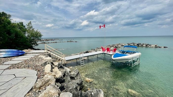 An overview of clear waters and a aluminum pipe dock with various accessories such as shore steps, a ladder, a boat lift, and a flag pole.