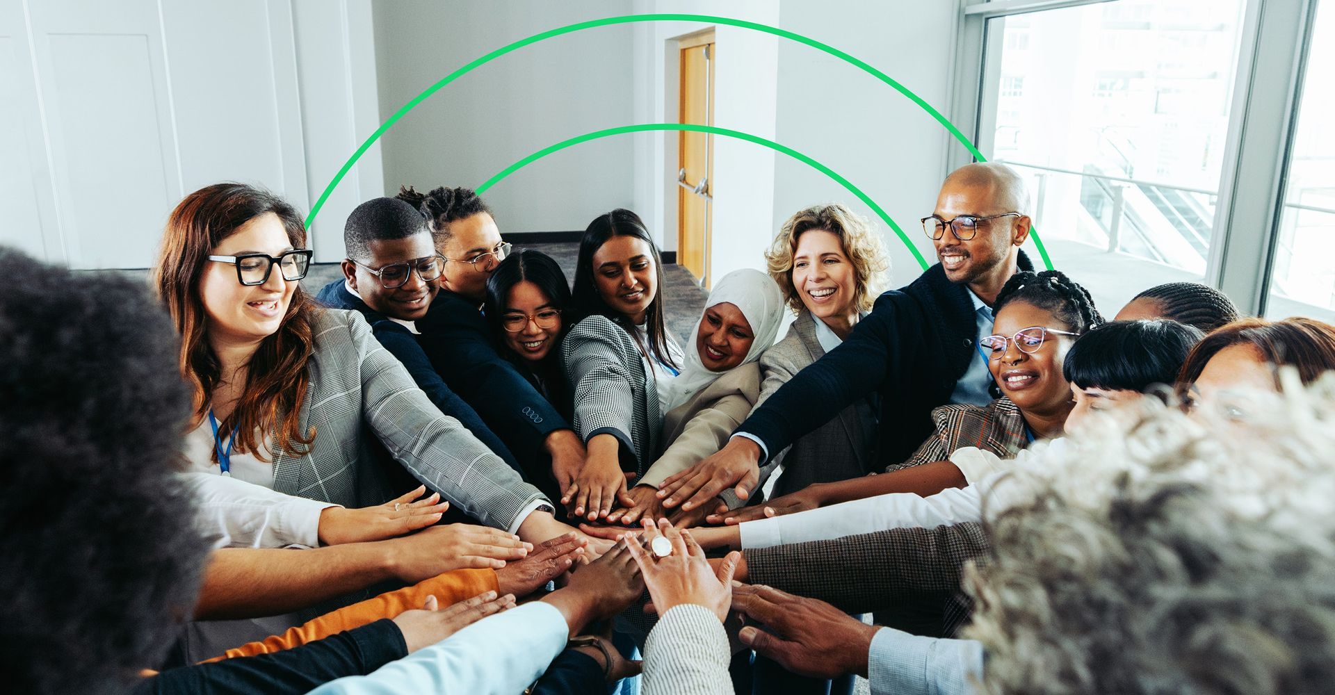 Group of smiling people putting their hands together in a circle.