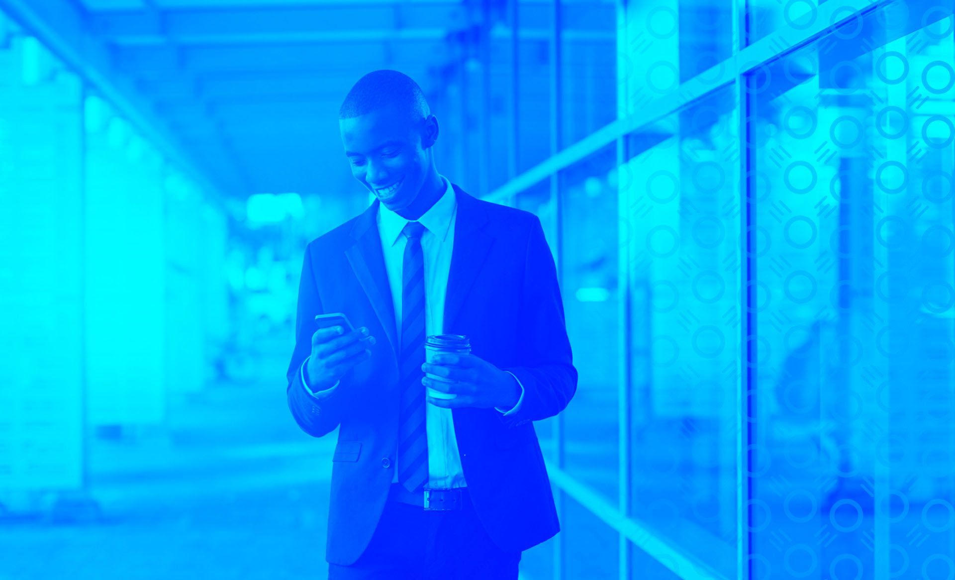 A man is on his phone in a suit with a blue background.