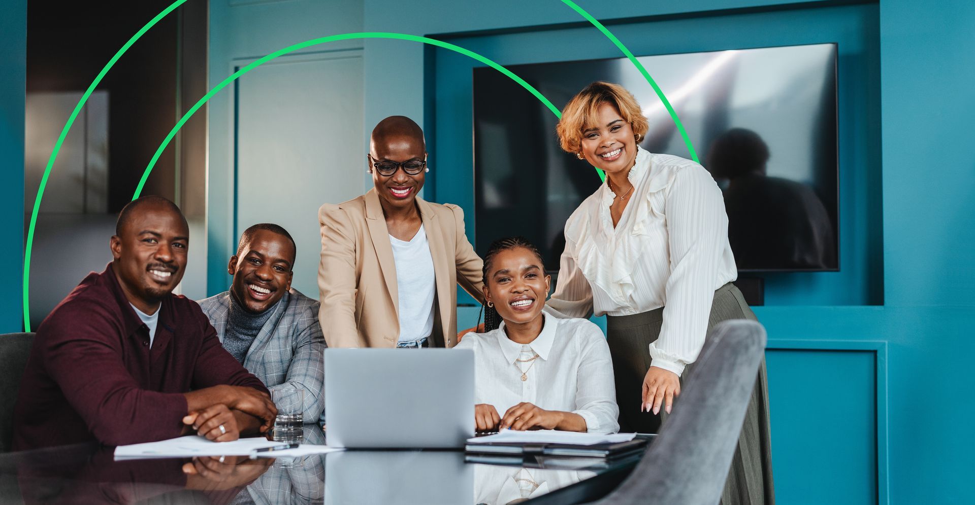 Smiling group of people sitting at a table working on a laptop