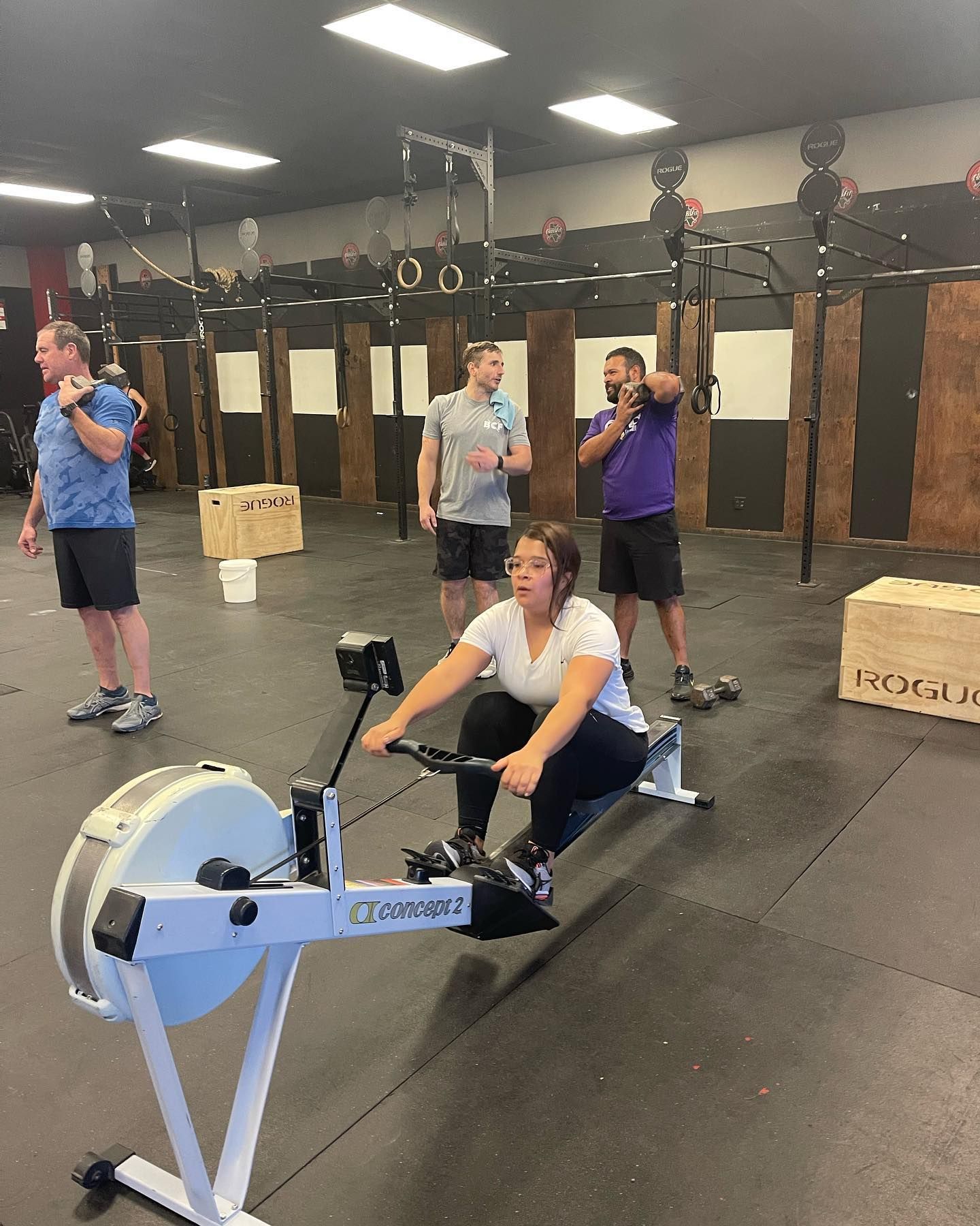 A woman is riding a rowing machine in a gym.