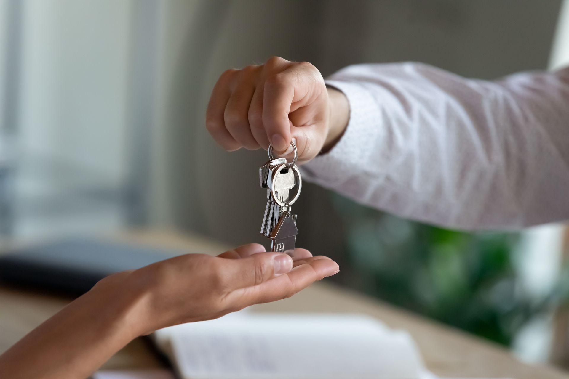 Person handing keys to another person; indoors, close-up.