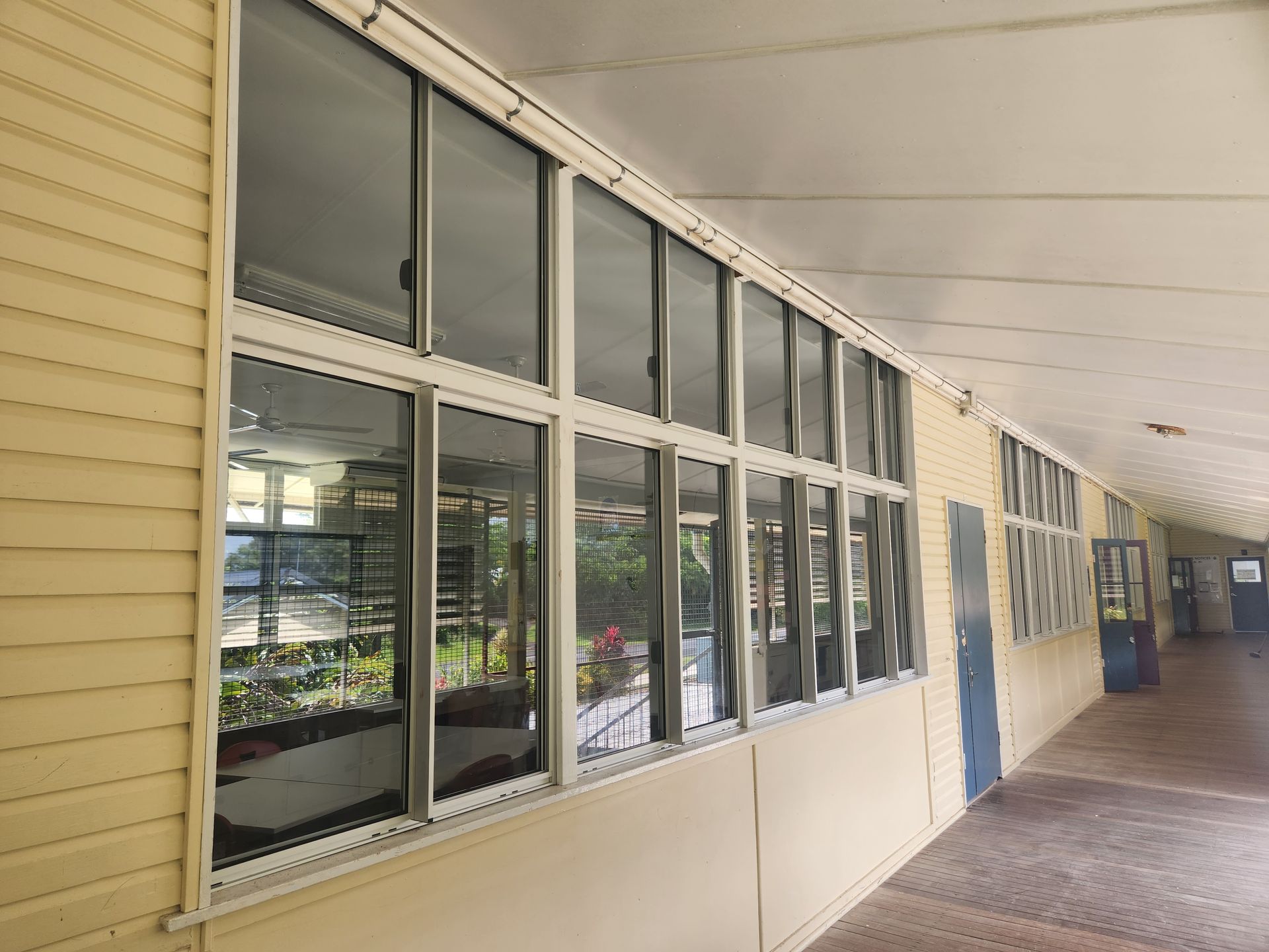 Long hallway with windows reflecting outside views. Pale yellow walls and roof 