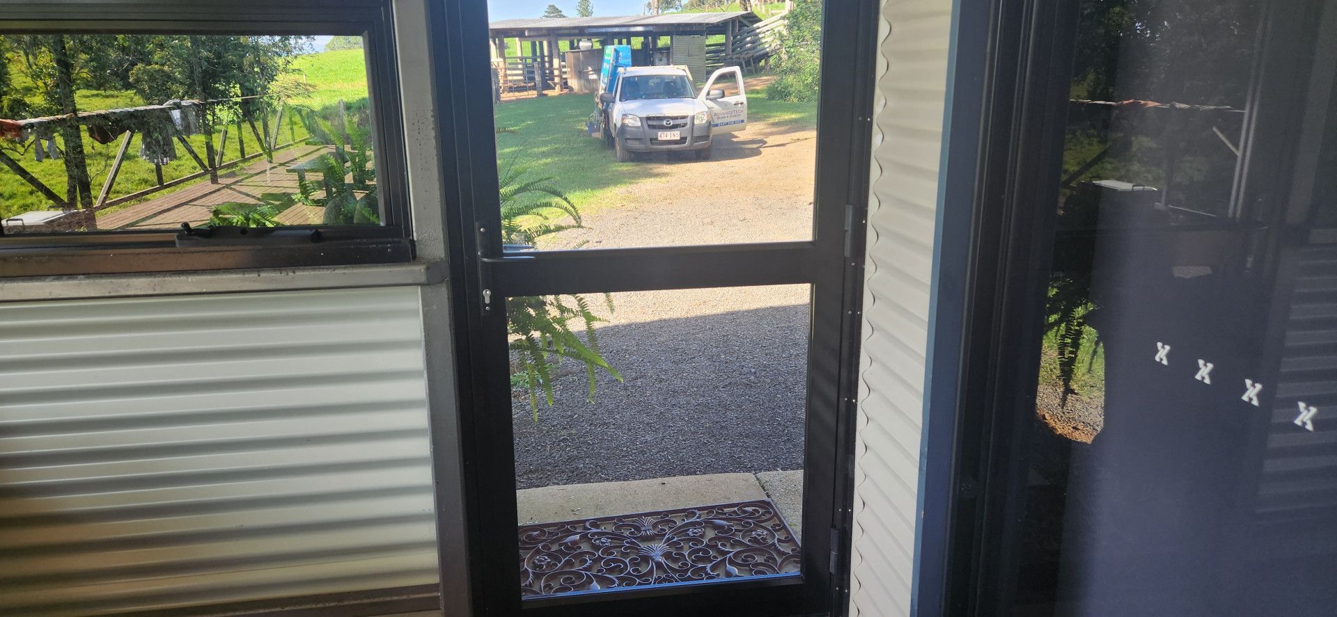 View From Inside A Building, Through A Screen Door, Towards A Driveway With A Vehicle — Advancetech Glass & Glazing in Wulguru, QLD