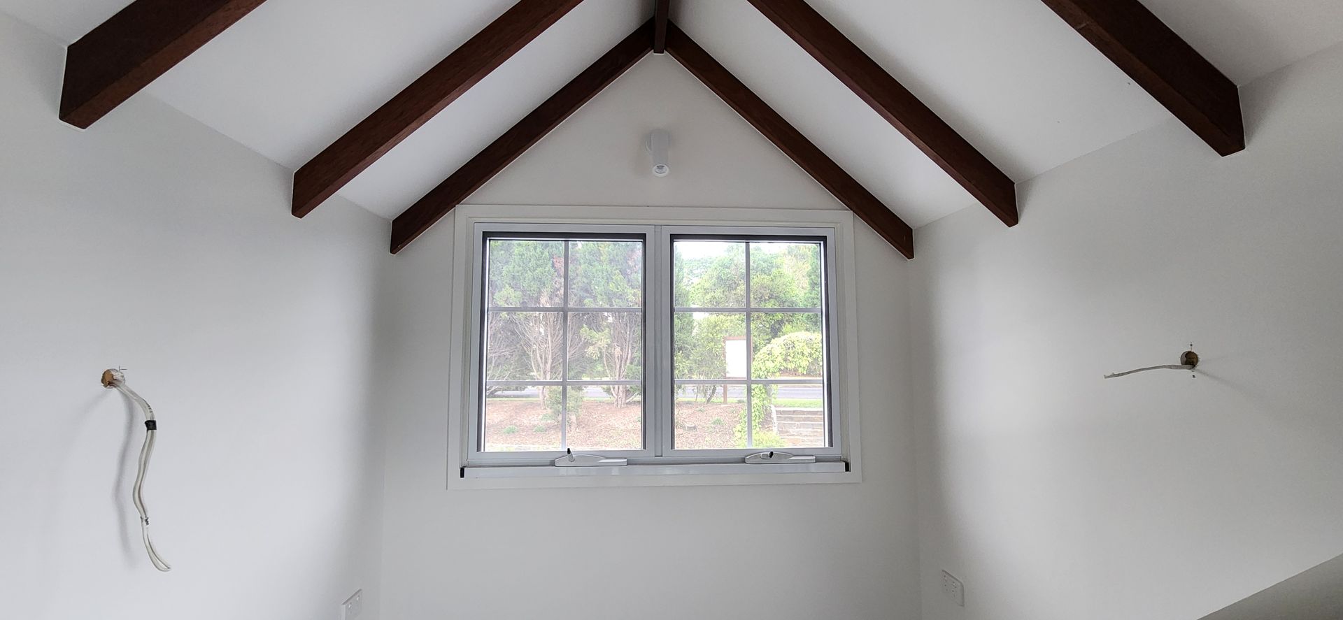 Interior View Of A Room With A Window And Exposed Wooden Beams On The Ceiling. White Walls — Advancetech Glass & Glazing in Wulguru, QLD