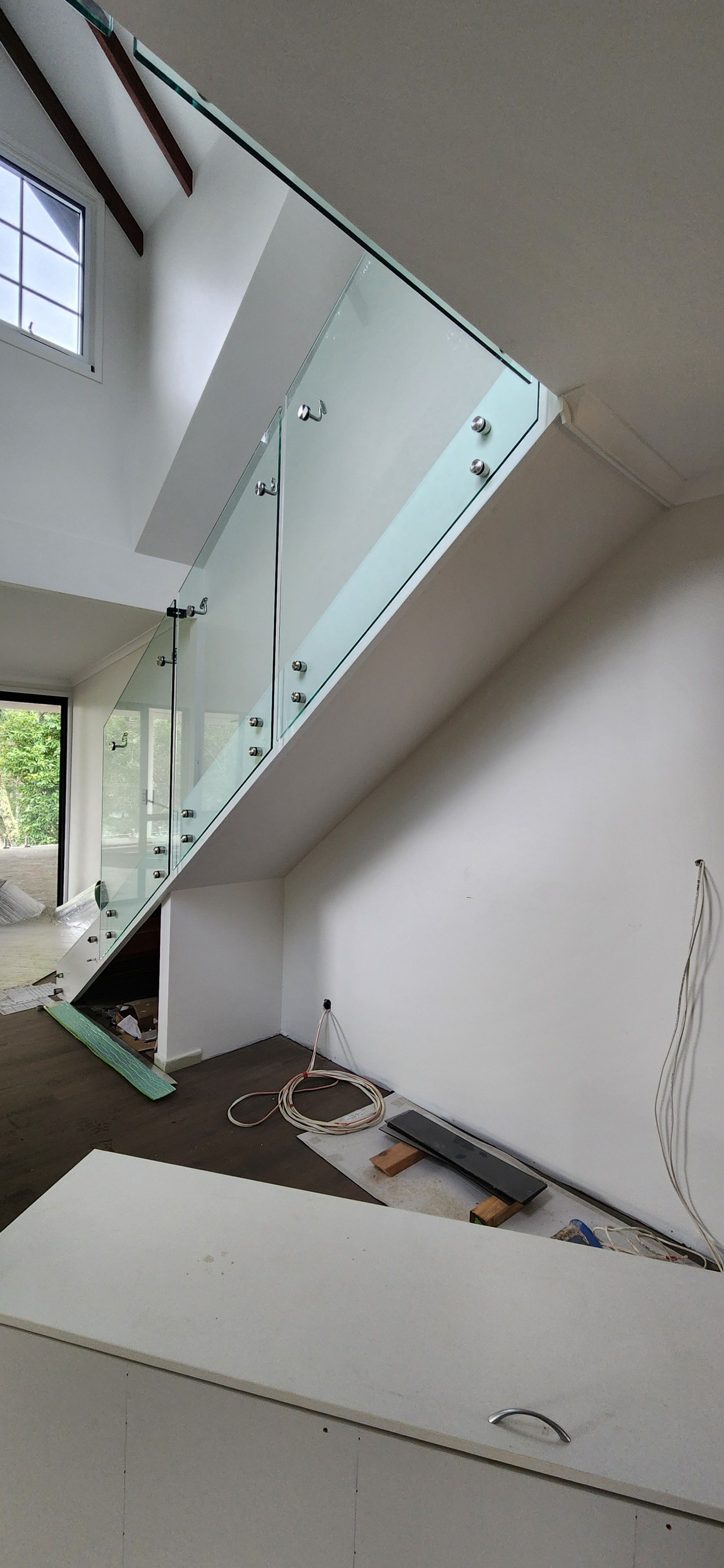 Interior of a room with a pitched ceiling, dark wooden beams, a window, and white walls — Advancetech Glass & Glazing in Wulguru, QLD
