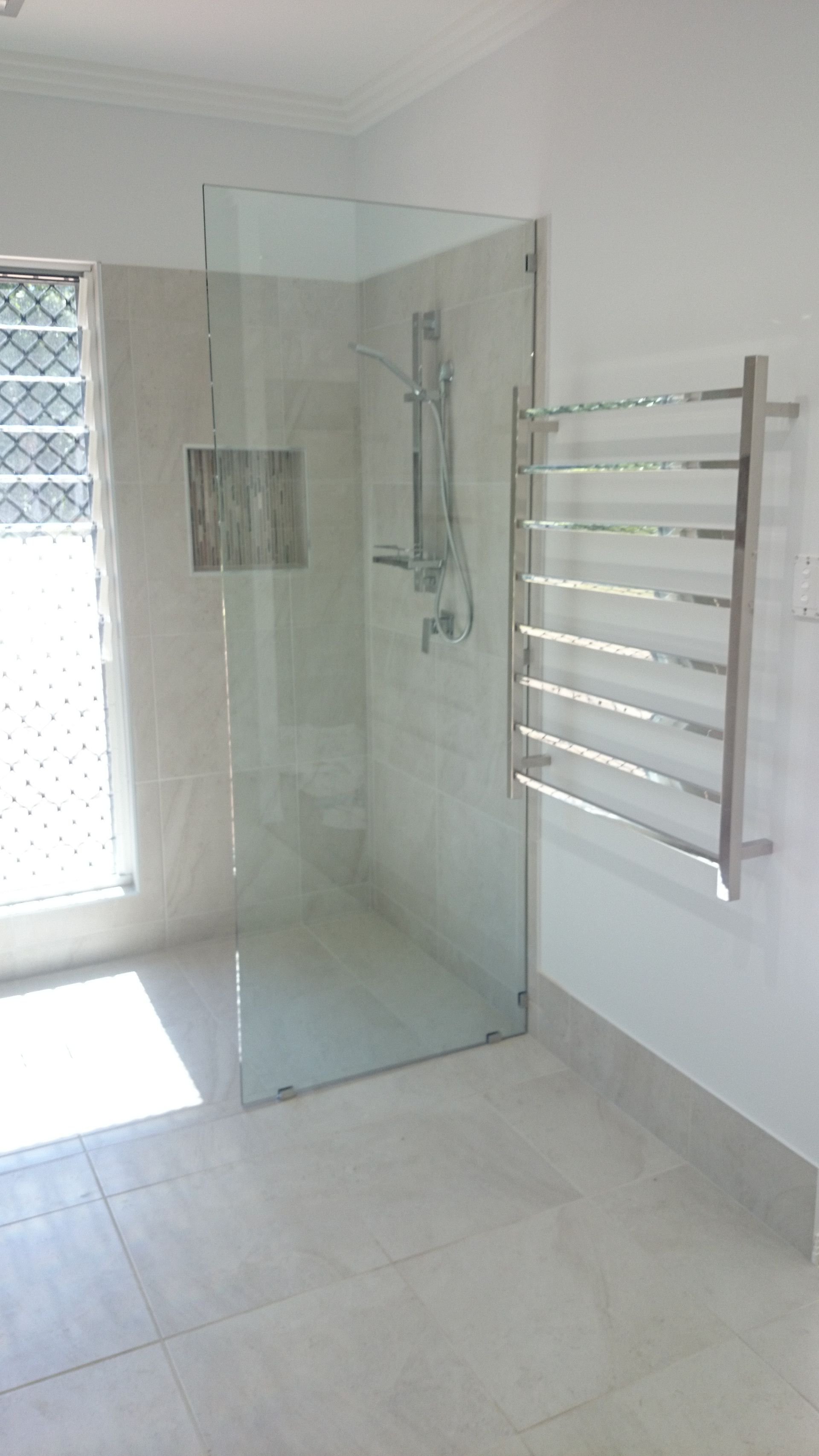 Bathroom with a frosted glass shower, white toilet and vanity, and overhead rain shower head 