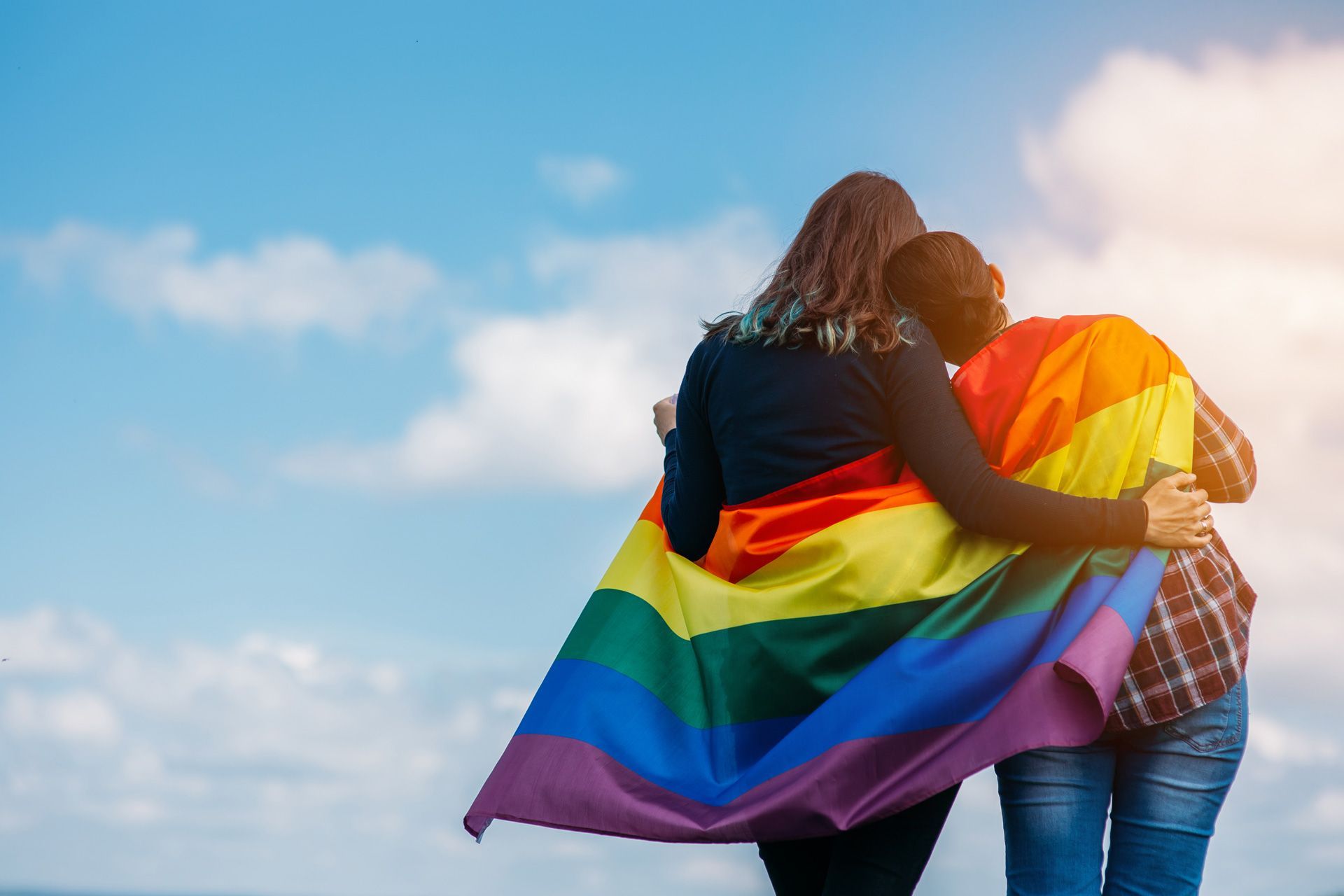 a couple of people standing next to each other holding a rainbow flag .