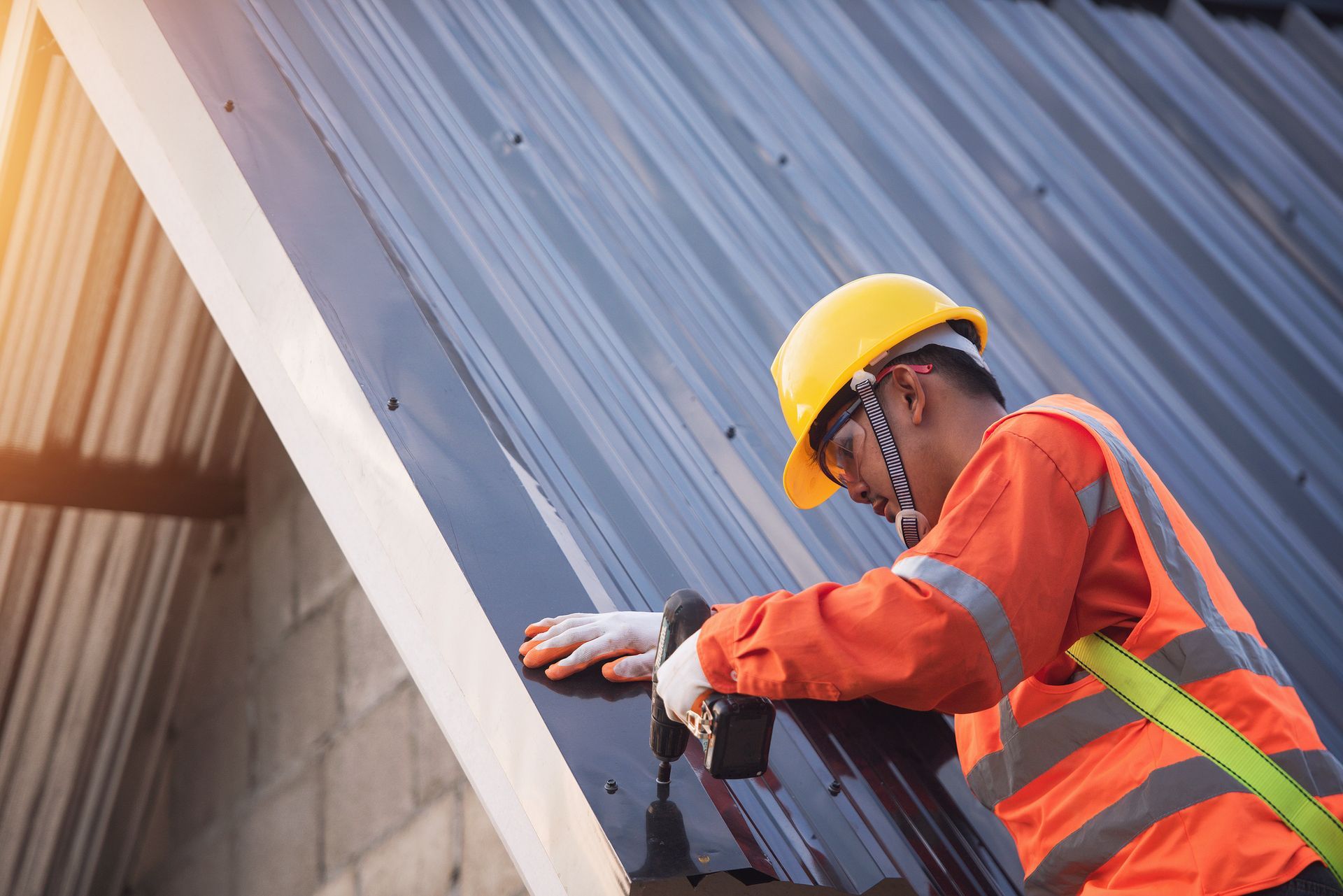 Construction worker installing metal roofing with drill for residential roof repair.
