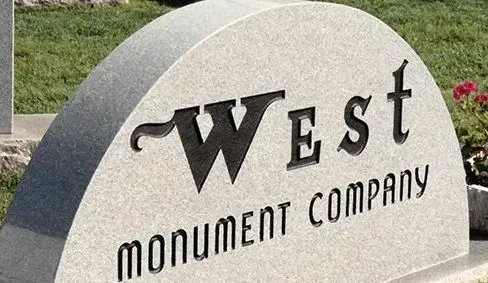 West Monument Company logo on a gray stone sign outdoors